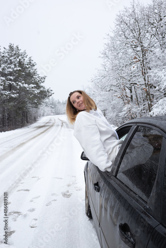 beautiful woman looks out of the car window on the background of a snowy forest