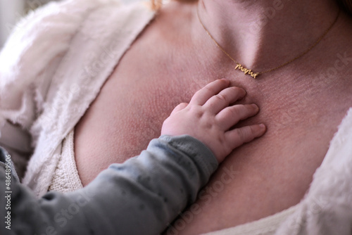 The baby is holding his mom, tiny baby hand touch mom 