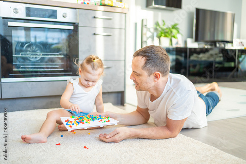 Cute little girl playing with mushroom nail mosaic. Father and baby playing together concept. Hobby and leisure time. 