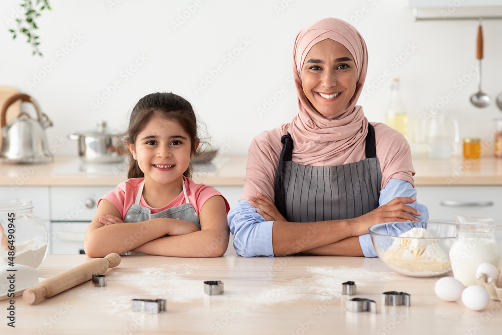 Baking Squad. Happy Islamic Mother And Little Daughter Cooking Pastry In Kitchen Baking Squad. Happy Islamic Mother And Little Daughter Cooking Pastry In Kitchen