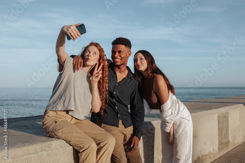 Three friends taking a selfie together next to the sea
