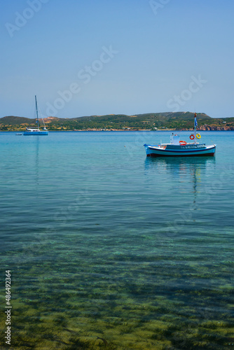 Greek fishing boat moored in blue waters of Aegean sea in harbor of near Milos island, Greece