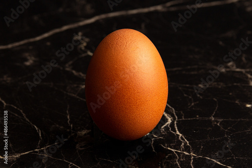 One chicken fresh egg close-up on a dark marble background photo