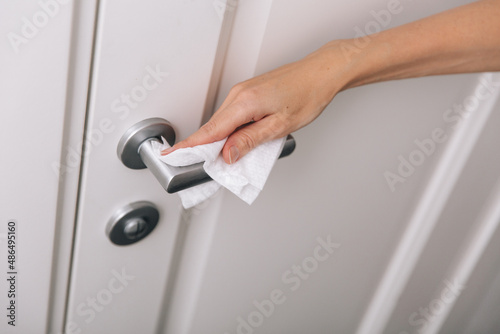 Cleaning door handles with an antiseptic wet wipe and gloves. Sanitize surfaces prevention in hospital and public spaces against corona virus. Woman hand using towel for cleaning home room door link