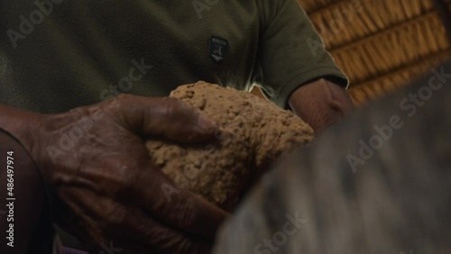 Dark-skinned hands molding and kneading guarana seed paste into a cylinder or bastao as part of the traditional processing method photo