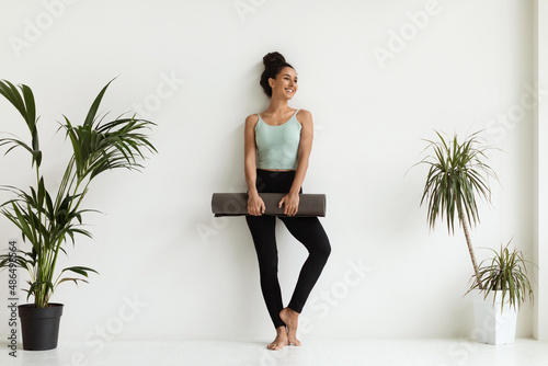 Portrait Of Sporty Young Female In Activewear With Fitness Mat In Hands