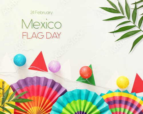 Mexico flag day. Congratulation holiday card with paper fans, garlands in the colors of Mexico on a white background with palm leaves and inscription Mexico Flag Day photo