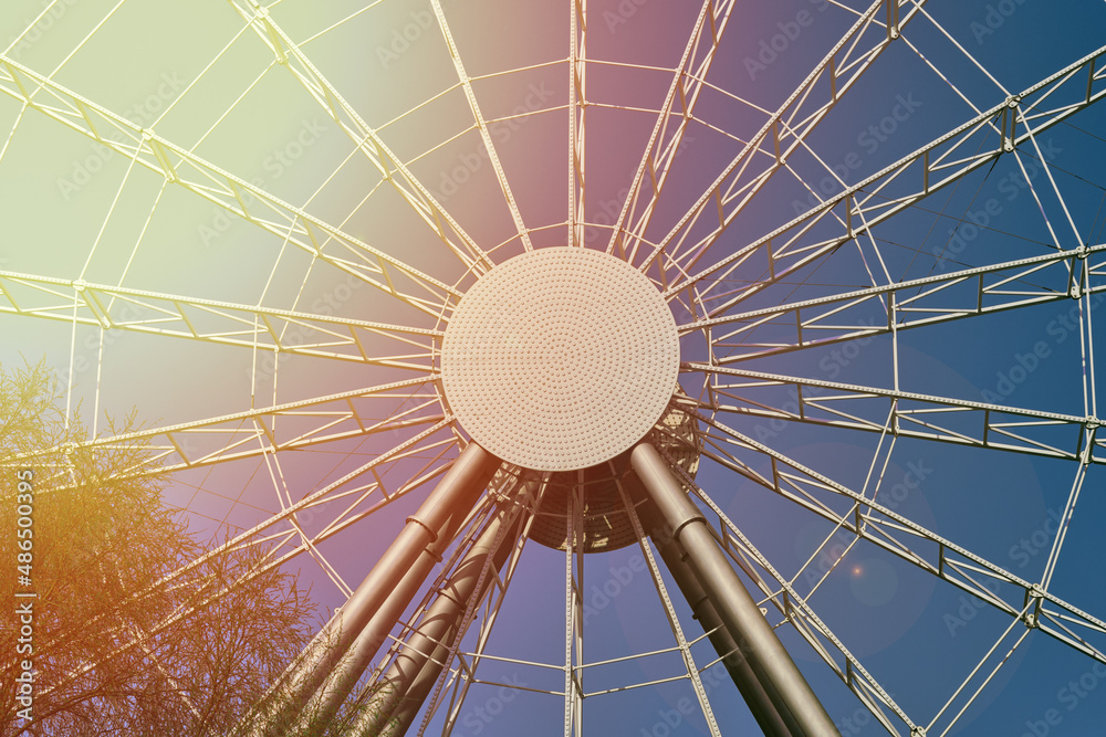 Ferris wheel on the background of a beautiful sky . An attraction in the rays of the sun .
