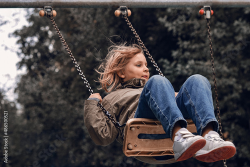 A girl of ten years is swinging on a swing. The child is playing on the playground. photo