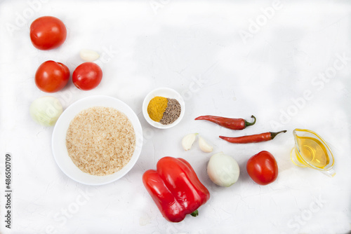 Rice, vegetables and spices for cooking jollof rice on a white background. Copy spaes.