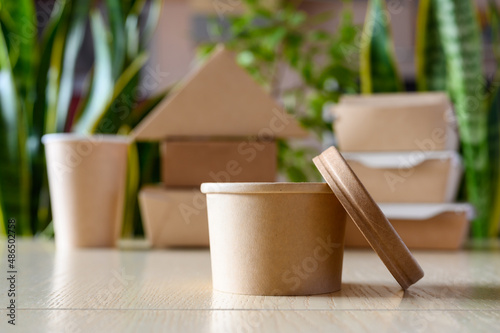 Eco-friendly tableware to save the environment. Round paper container for soup against the background of disposable tableware and green plants. photo