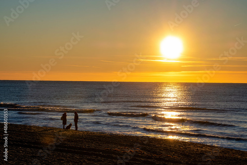 Ein Paar mit Hund beobachtet den Sonnenuntergang am Meer © Dieter