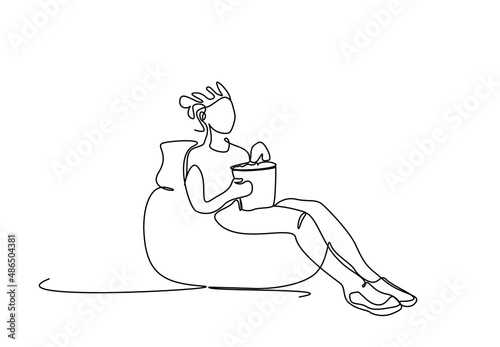 beautiful woman sitting on pear puj sofa watching movie excitedly and eating popcorn