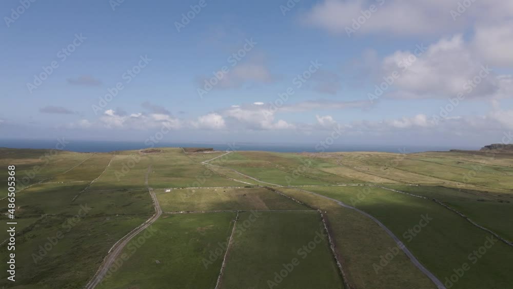 Drone shot of green fields on a summers day with the ocean in the background. Drone shot of green fields on a summers day with the ocean in the background.