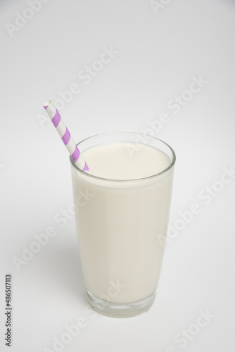 Milk glass with colored straw close-up on a white background