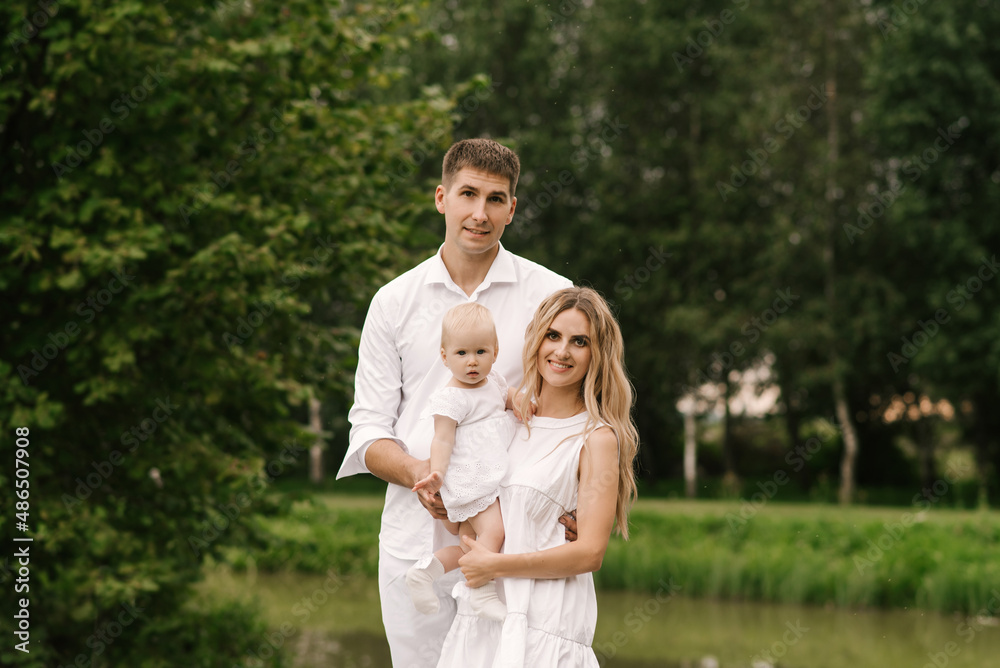 Beautiful young family mom and dad with one-year-old daughter in nature, happy family Beautiful young family mom and dad with one-year-old daughter in nature, happy family