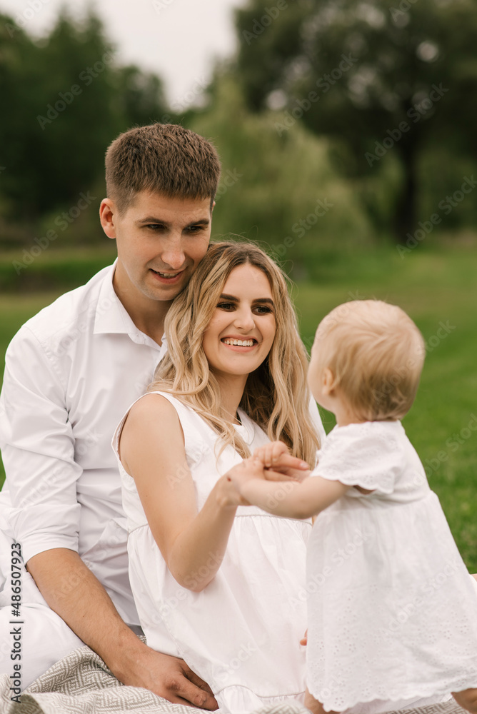 Beautiful young family mom and dad with one-year-old daughter in nature, happy family Beautiful young family mom and dad with one-year-old daughter in nature, happy family