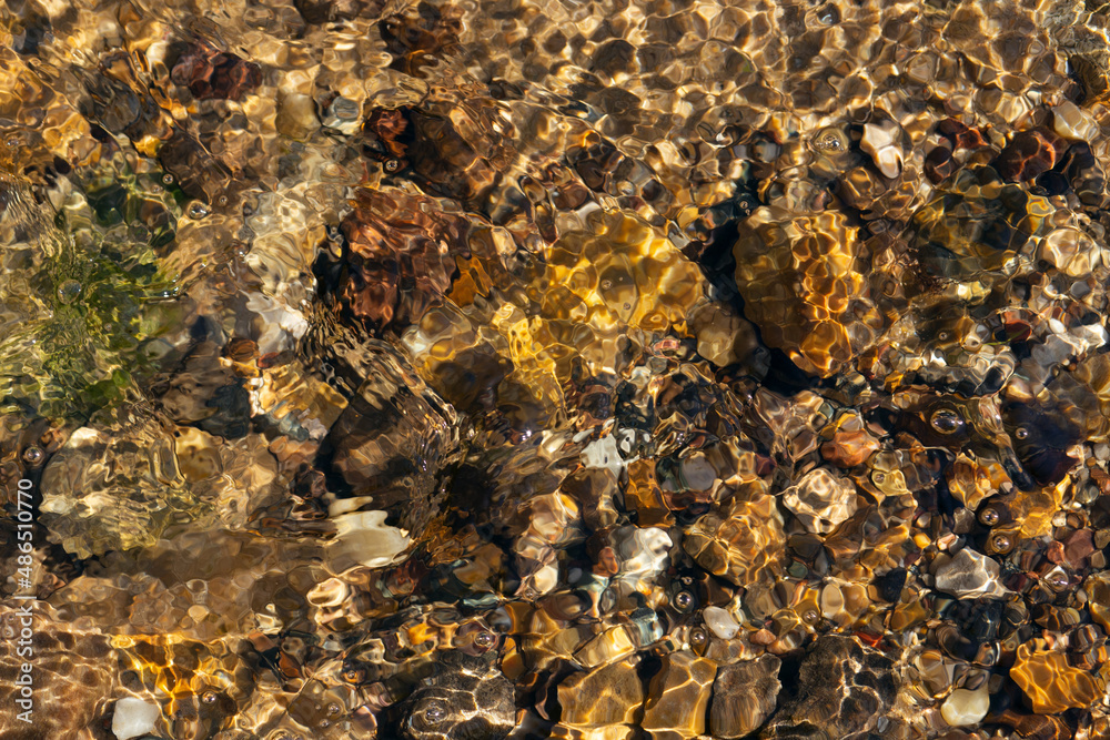 Close-up of the bottom of a shallow stream, stones, rapids. Sun glare on the water, frozen motion of the current.
Close-up of the bottom of a shallow stream, stones, rapids. Sun glare on the water, frozen motion of the current.