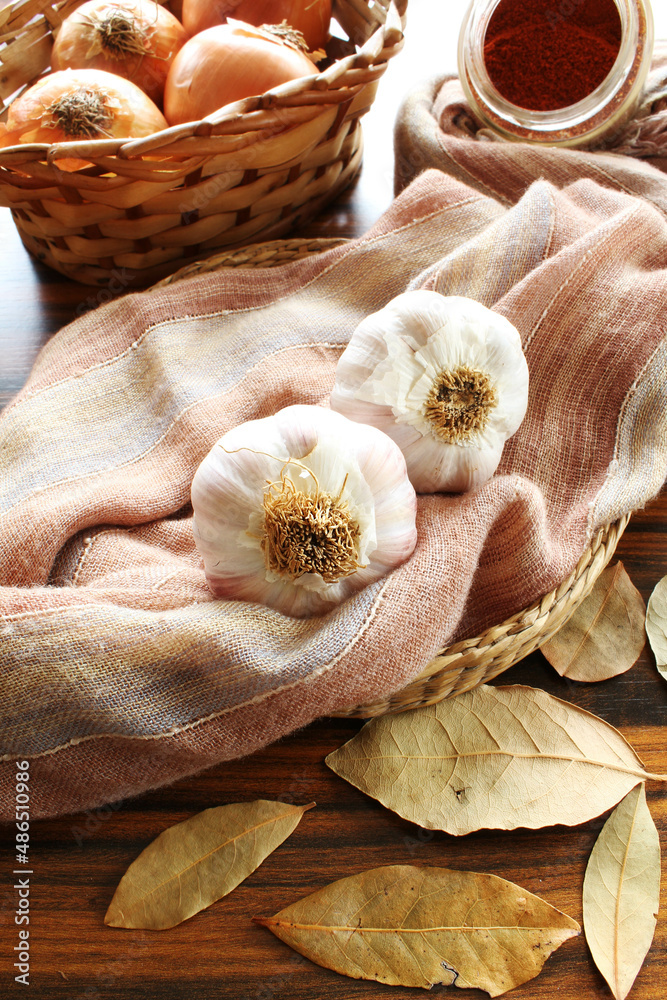Closeup of garlic bulb on fabric with seasonings paprika powder onions and dried laurel. Seletive focus.