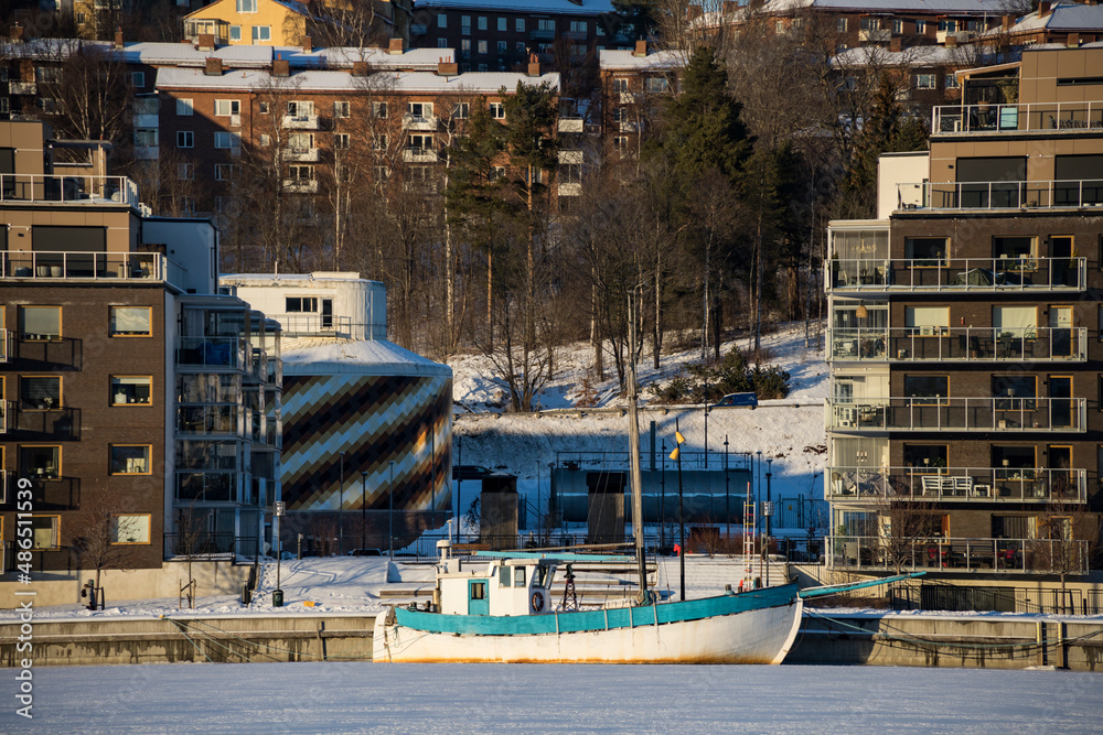 Naklejka premium Sundsvall, Sweden A residential apartment building in the Sundsvall harbour and a boat in the ice.