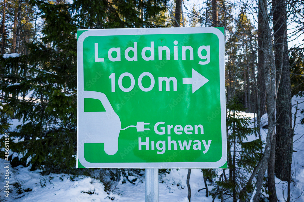 Fototapeta premium Sundsvall, Sweden A green street sign pointing towards an electrical charging station for cars. Laddning in Swedish means charging.