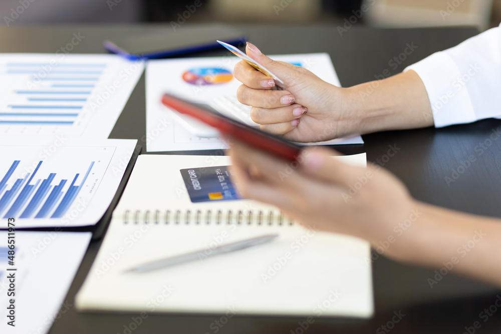 Woman holding credit card and using mobile phone shopping online. Close-up woman holding credit card and using mobile phone for online financial transactions. Woman holding credit card and using mobile phone shopping online. Close-up woman holding credit card and using mobile phone for online financial transactions.