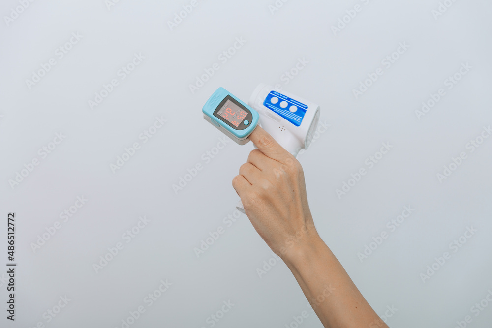 Pulse oximeter and thermometer gun on white background. Measuring oxygen saturation, pulse rate and oxygen levels. Infrared isometric thermometer gun to check body temperature for virus symptoms Pulse oximeter and thermometer gun on white background. Measuring oxygen saturation, pulse rate and oxygen levels. Infrared isometric thermometer gun to check body temperature for virus symptoms