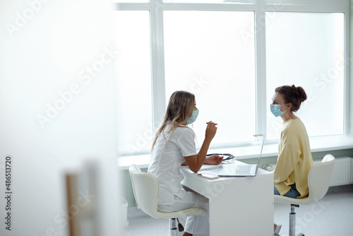 Female doctor in medical facial mask have consultation with patient during covid-19 pandemics. Woman in facemask talk consult  client in clinic or hospital. Coronavirus concept.