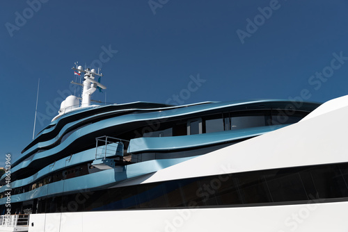 Bottom view of decks of huge yacht of blue color at sunny day, glossy board of the motor boat, sun reflection on glossy board, blue sky is on background photo