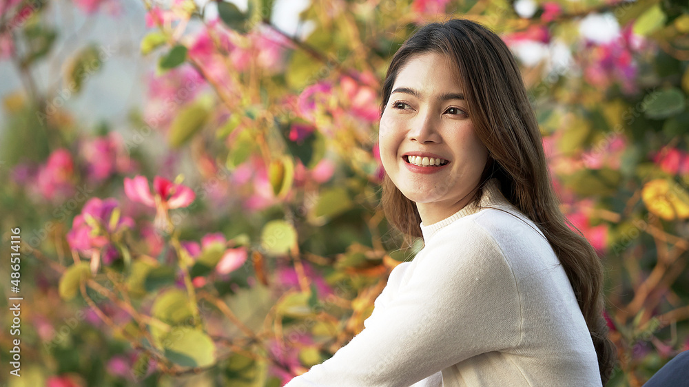 Young Asian woman smiling beautifully and looking to the camera with beautiful flower background. Young Asian woman smiling beautifully and looking to the camera with beautiful flower background.