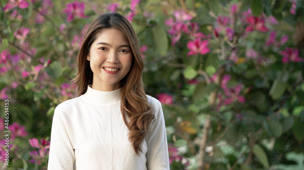 Young Asian woman smiling beautifully and looking to the camera with beautiful flower background. Young Asian woman smiling beautifully and looking to the camera with beautiful flower background.