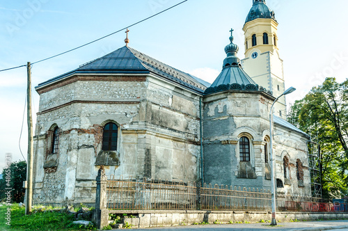 Serbian Ortodox Episcopal Church in Poor Condition Located in Plaski, Croatia. Damaged Building Surrounded by Railings and Grass photo