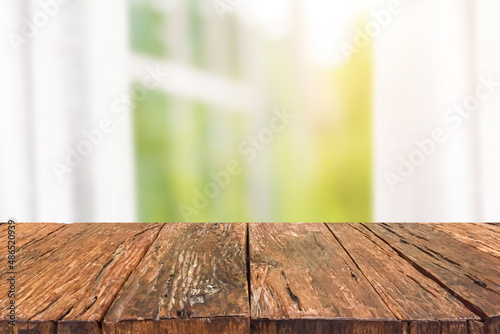 Empty old wooden table top front of blurred white curtains, window, tree and sunlight background. Can be used for display or montage your products.Mock up for display of product.