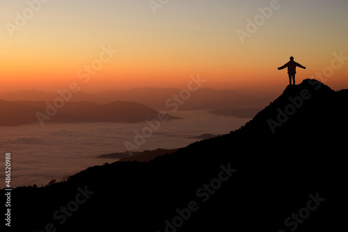Young backpacker with looking and enjoying sunrise on top of mountain. She strong confidence woman open arms under the sunrise. She enjoyed traveling and was successful when he reached the summit.
