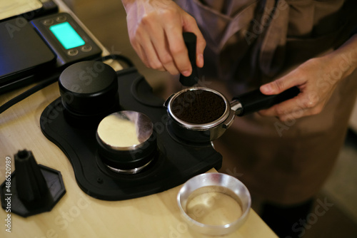 Professional barista prepare grinded coffee into portafilter for espresso brewing process