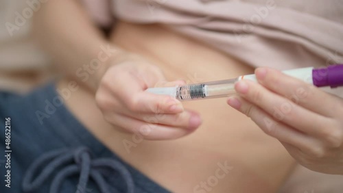 A woman insert needle into the syringe before injection drug at stomach skin. IVF concept. Person in vitro fertilization treatment injection hormone for pregnancy.