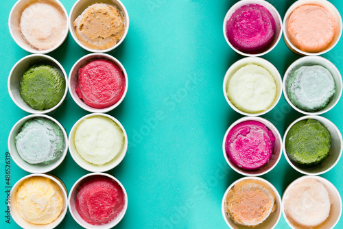 Top view of Ice cream flavors in cup and topping on green table background, sweet and dessert food concept