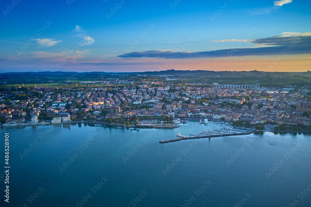 Fototapeta premium Top view of the boat parking on the lake. Italian resorts on Lake Garda. Aerial view of Desenzano del Garda. Aerial panorama of the town of Desenzano del Garda on Lake Garda in Italy.