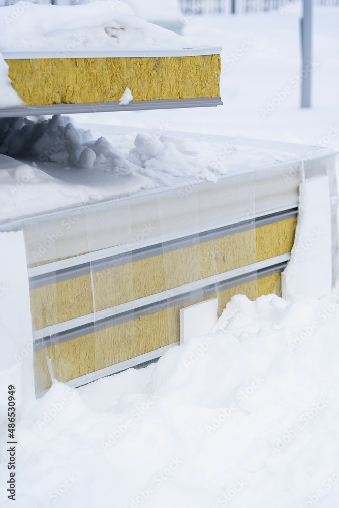 Insulated sandwich panels lie on the ground under the snow, vertical photo Insulated sandwich panels lie on the ground under the snow, vertical photo