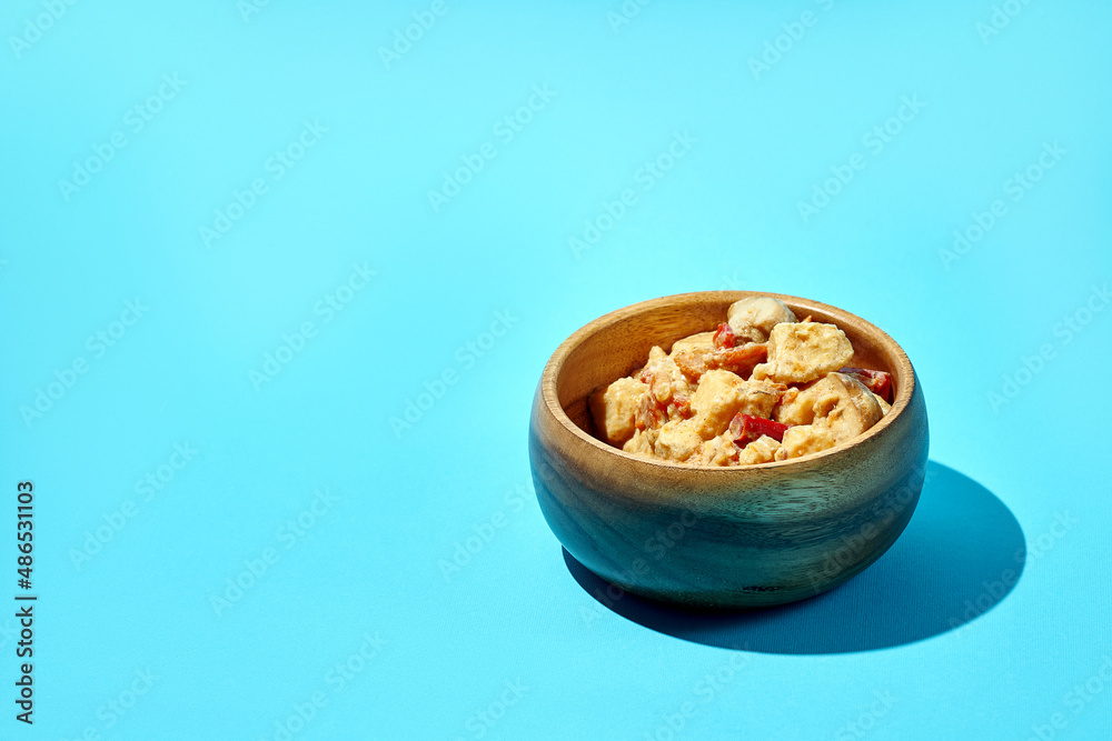 Stewed potatoes with meat and mushrooms in a wooden bowl on a blue background Stewed potatoes with meat and mushrooms in a wooden bowl on a blue background