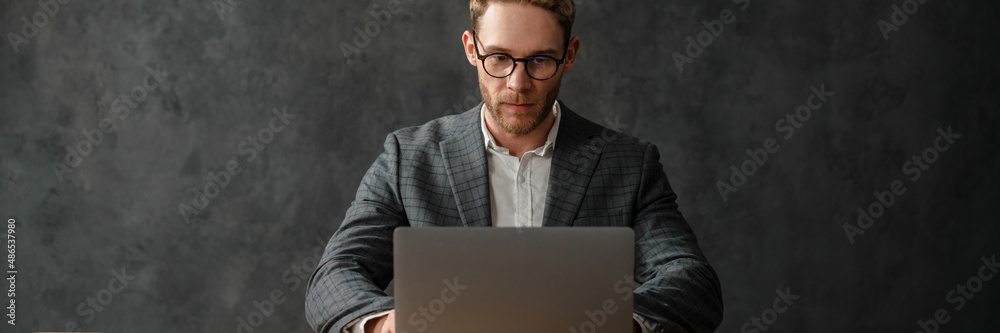 A man sitting in front of a laptop at a table in the studio A man sitting in front of a laptop at a table in the studio