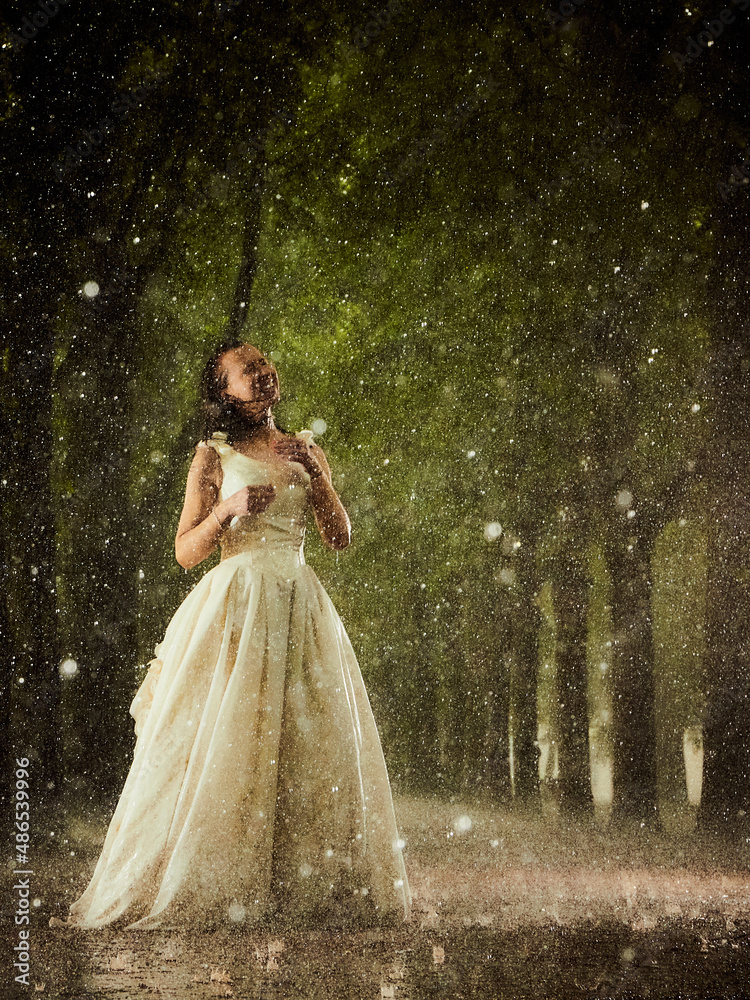 happy bride in a white wedding dress in the rain on an alley under big ...