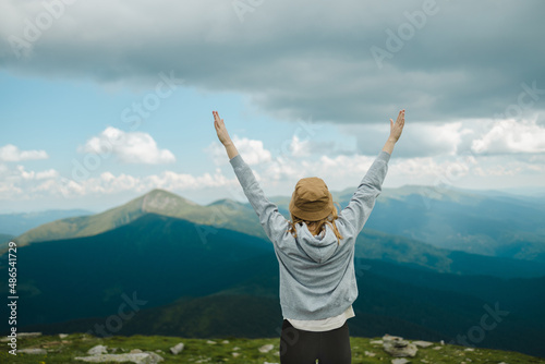 Beautiful hiker woman rise hand up on top of mountain and sunset sky background. Amazing Carpathians landscape background