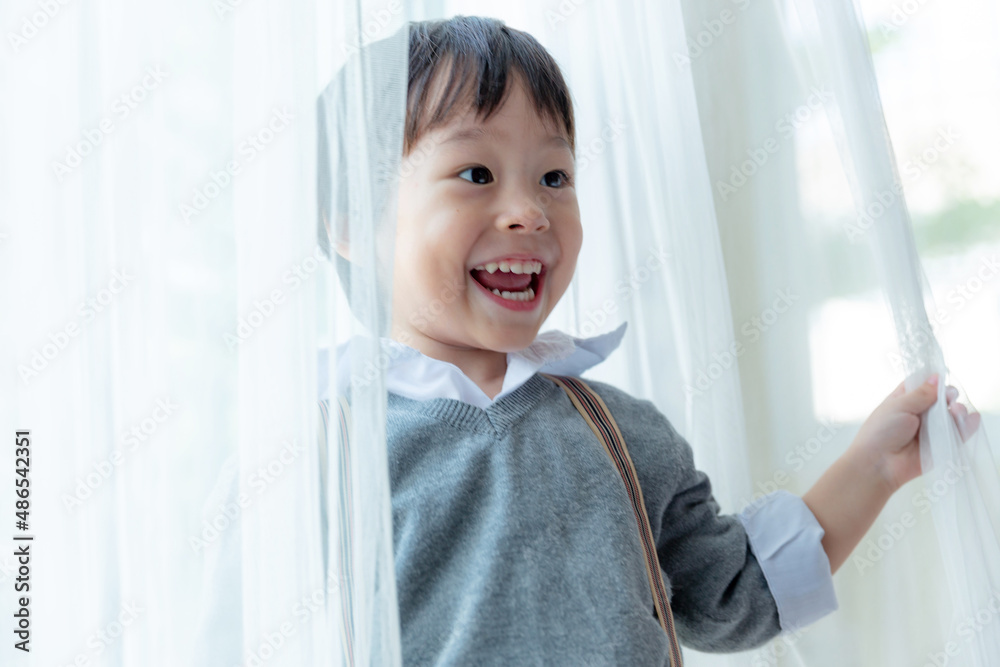 Happy cute little boy fun and enjoying playing and smiling with white curtain. Happy cute little boy fun and enjoying playing and smiling with white curtain.