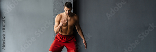 Young shirtless sportsman doing exercise with expander stretch tape