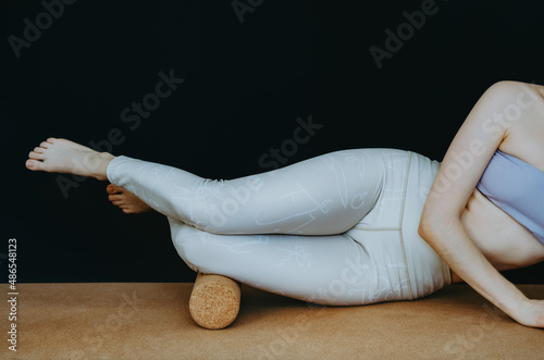 Person doing gentle myofascial release with cork roller on the IT band just above the knee. Concept: self care practices at home, knee pain relief photo