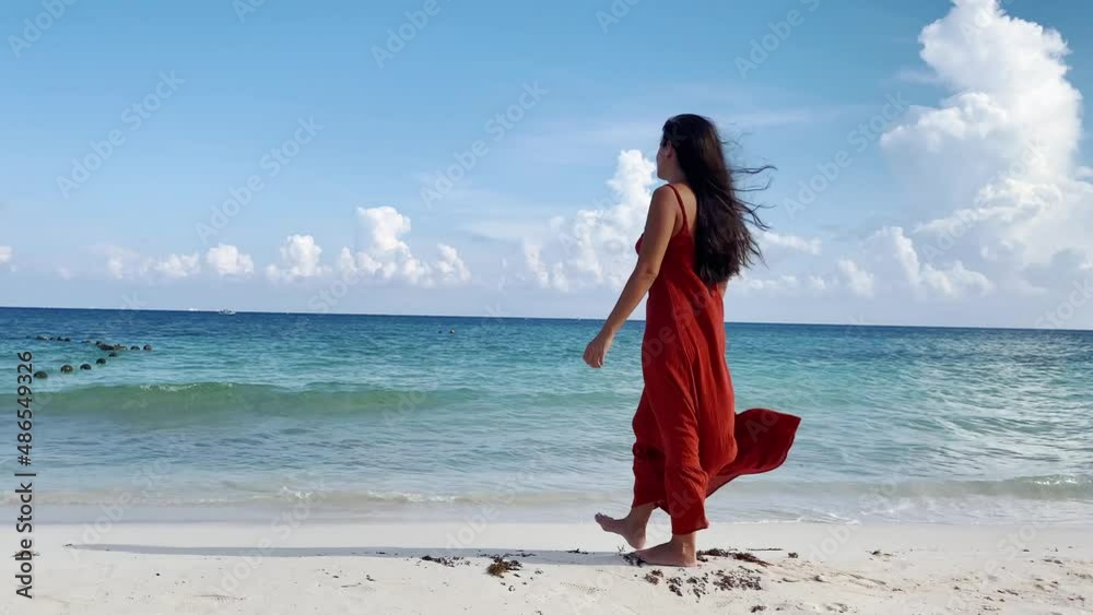 young hispanic woman in red dress walks along the shore of the caribbean sea young hispanic woman in red dress walks along the shore of the caribbean sea