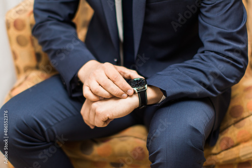 business man wearing a navy suit fixing his watch