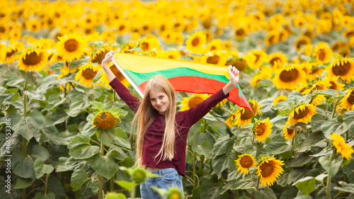 Girl holding flag of Lithuania in a sunflowers field. Lithuanian Flag Day. Independence restoration Day. Travel and love Lithuania concept. Selective focus. photo