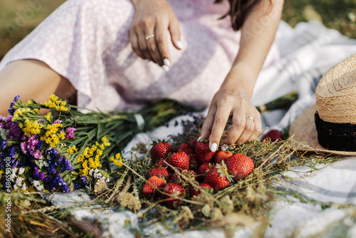 Fashionable girl with hat, strawberry and flowers in the garden